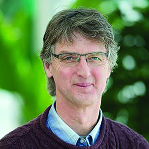 man with greying hair and glasses wearing a maroon sweater