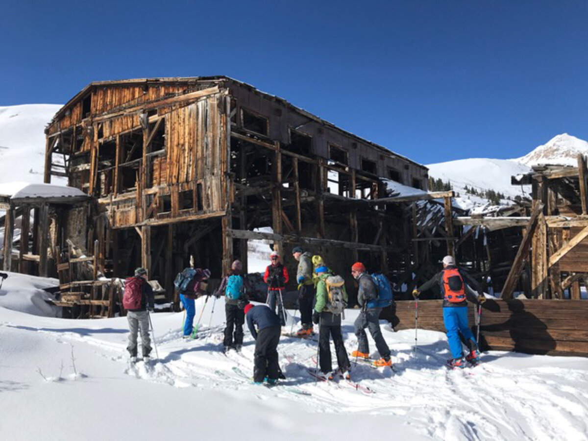 Backcountry skiers stop outside of the abandoned wooden mill