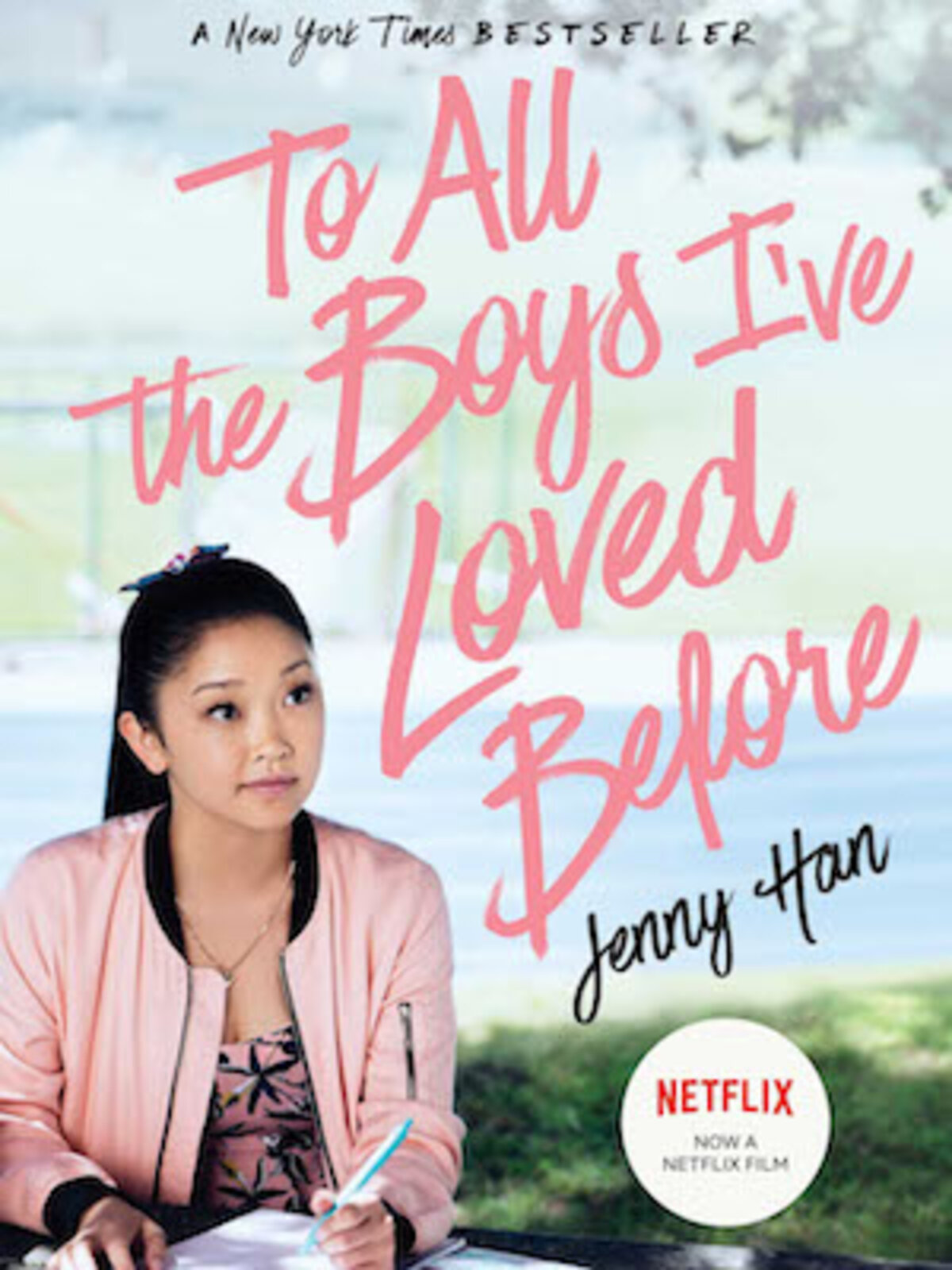 A teenage girl in a pink jacket sitting outside for To All The Boys I've Loved Before movie poster