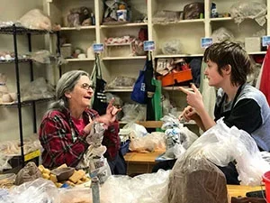 Two people signing in ASL in an art studio