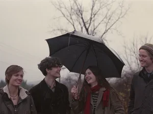 four students under an umbrella