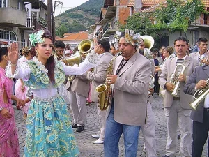 a brass band and ladies in colourful dresses in a street for a wedding celebration