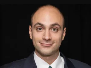 A bald man in a suit with a small smile on his face