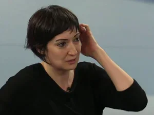 woman in black sweater against pale blue background