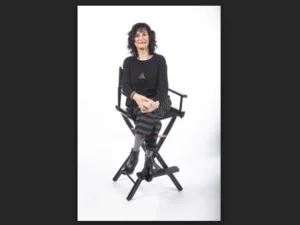 woman in striped pants sitting cross legged on a tall chair