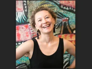 smiling woman in black tank top in front of very colourful backdrop