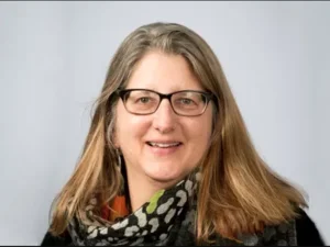 headshot of woman with glasses on grey background