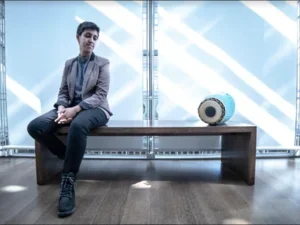 futuristic blue-toned photo of a young woman and a drum on a bench