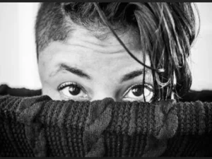 black and whit photo of the top of a head peaking out of a cloth basket