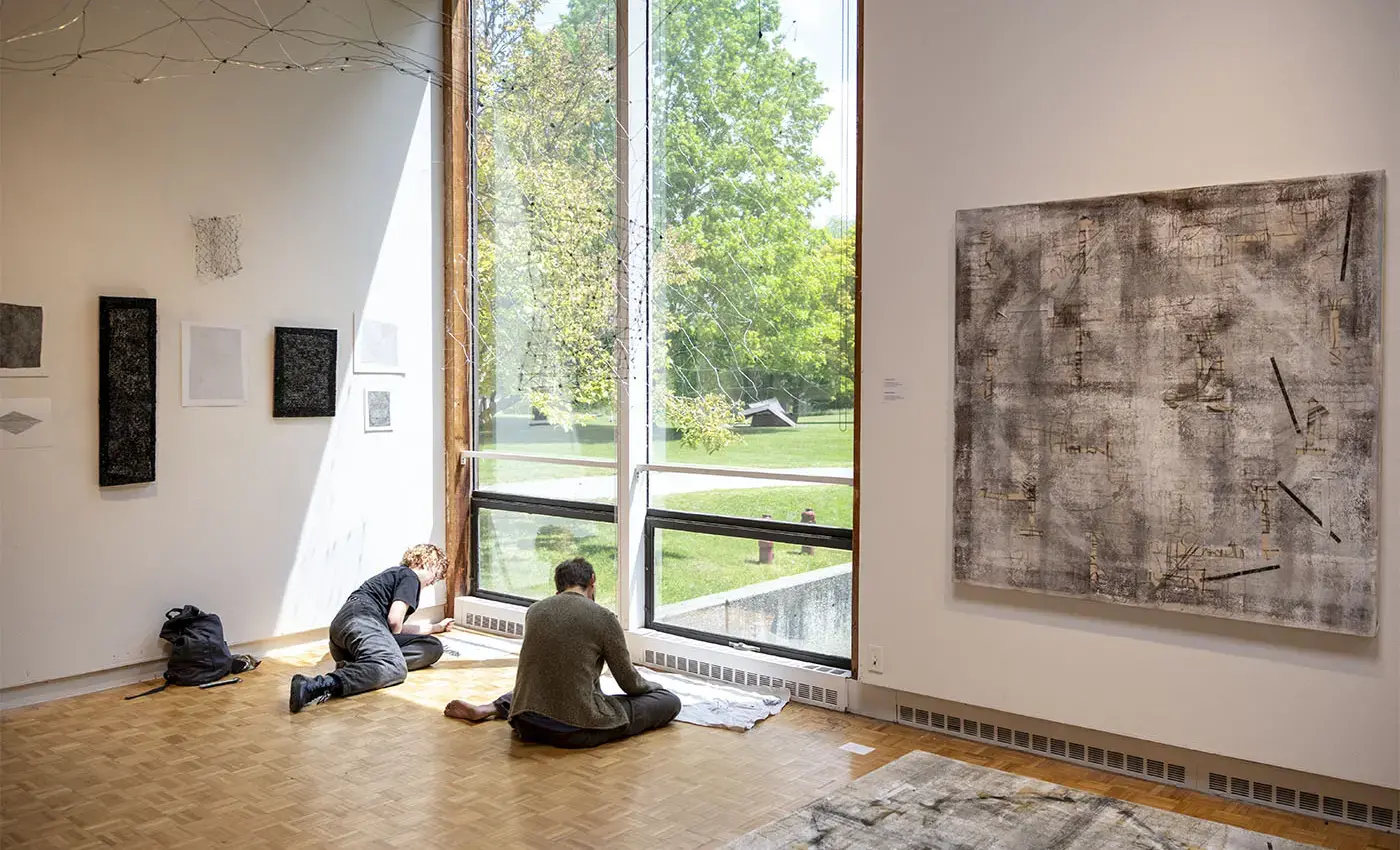 students sketching in a natural light-filled gallery where an exhibition is displayed