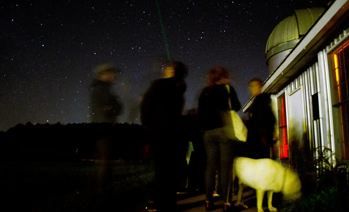 Students observing night sky outside observatory