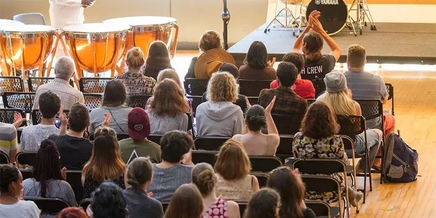 students sitting in an audience clap