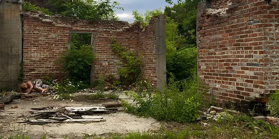 brick courtyard in abandoned ruin with dancer performer lying on the dusty ground