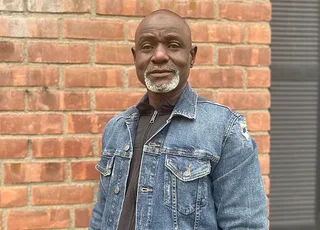 Souleymane Badolo in a jean jacket in front of brick wall